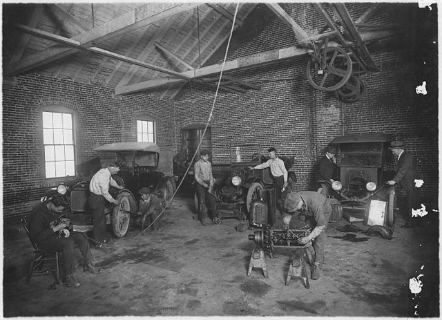 Автомобильная мастерская в Канзасе в двадцатых годах 20 века (Источник: https://fr.wikipedia.org/wiki/Atelier_de_reparation_automobile#/media/Fichier:Students_at_work_in_auto_repair_shop_-_NARA_-_285366.jpg)